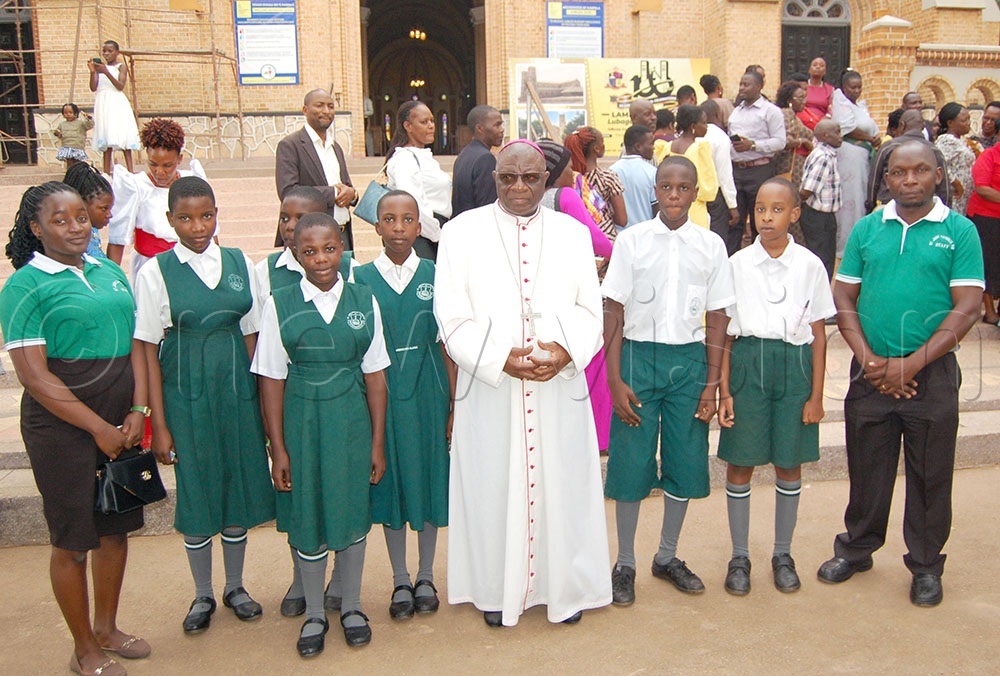 Archbishop Paul Ssemogerere (wearing a white cassock) shares a photo moment wth the pupils and teachers of  St Jude Primary School Wakiso who graced the function. (Credit: Mathias Mazinga)