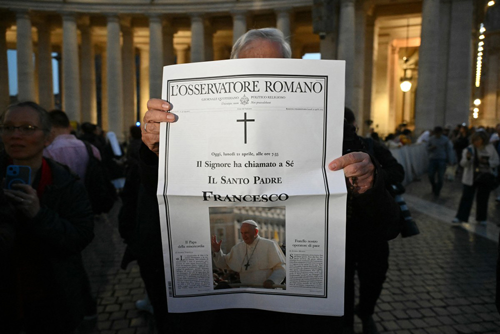 A priest holds a copy of a special edition of the Vatican newspaper L'Osservatore Romano announcing the death of the Pope Francis in Saint Peter's Square, the Vatican. (AFP Photo)