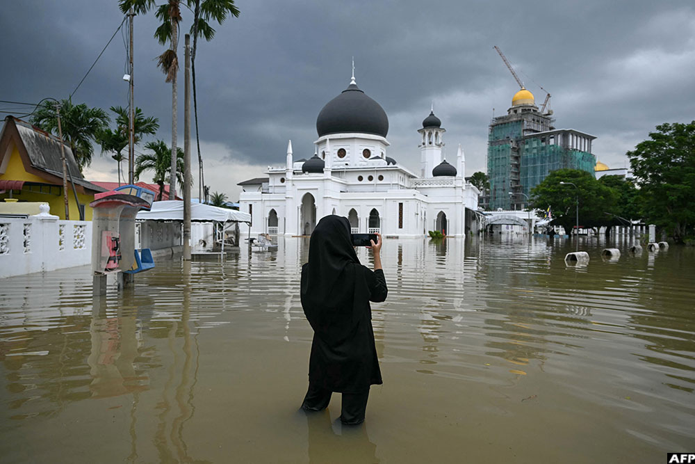 A woman takes a photo of a flooded mosque in Kangar in northern Malaysia's Perlis state on November 27, 2025