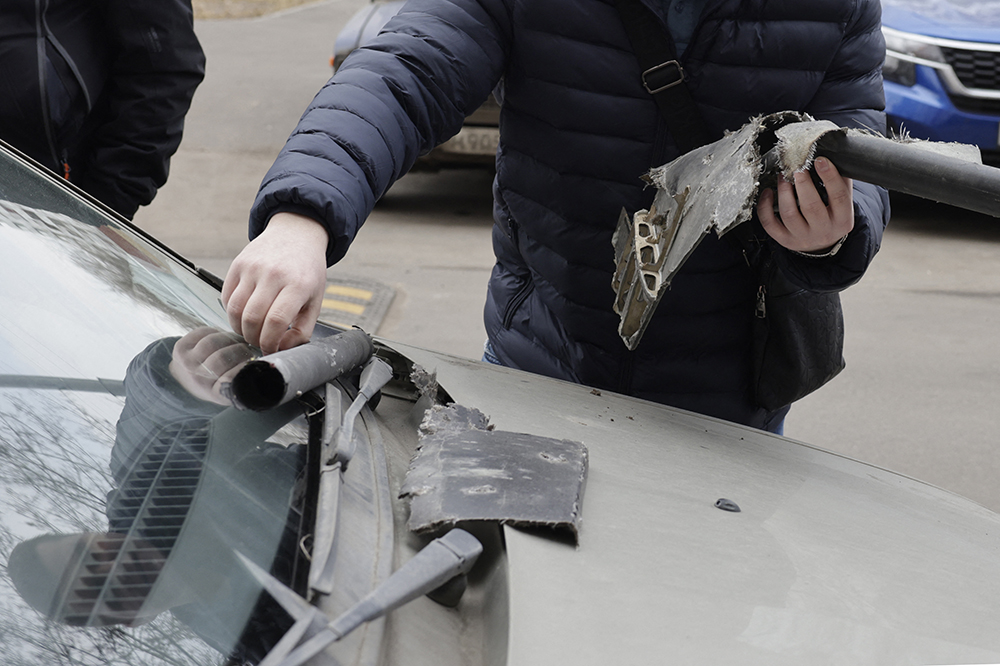 A man removes what is said the remains of a downed drone from a car in the yard of a damaged apartment building following a drone attack in Moscow on March 11, 2025. (Credit: AFP)