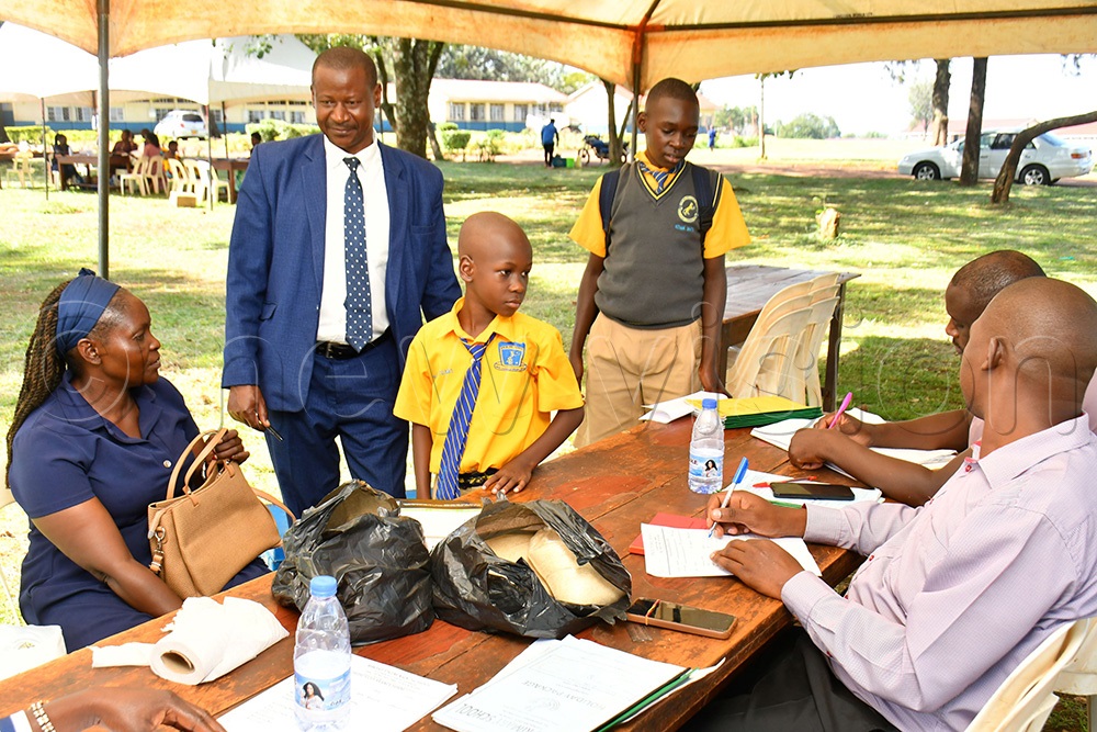 The Headmaster of Mwiri Boarding Primary School Ronald Mwanga (2nd R) overseeing an exercise of receiving pupils as they reported back to their school for term two. (Photo by Donald Kiirya)