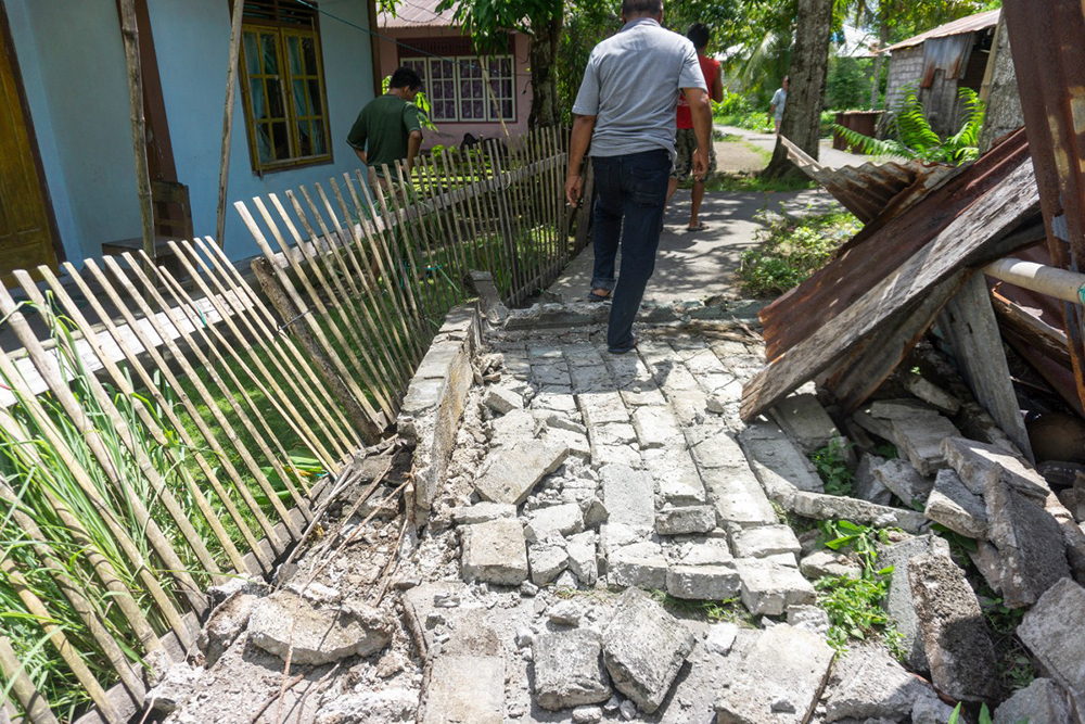 People past damage in a residential area caused by a magnitude 7.8 earthquake off the southern Philippines, at Peta Timur village in Sangihe Islands Regency, Indonesia's North Sulawesi province on June 8, 2026. (AFP)