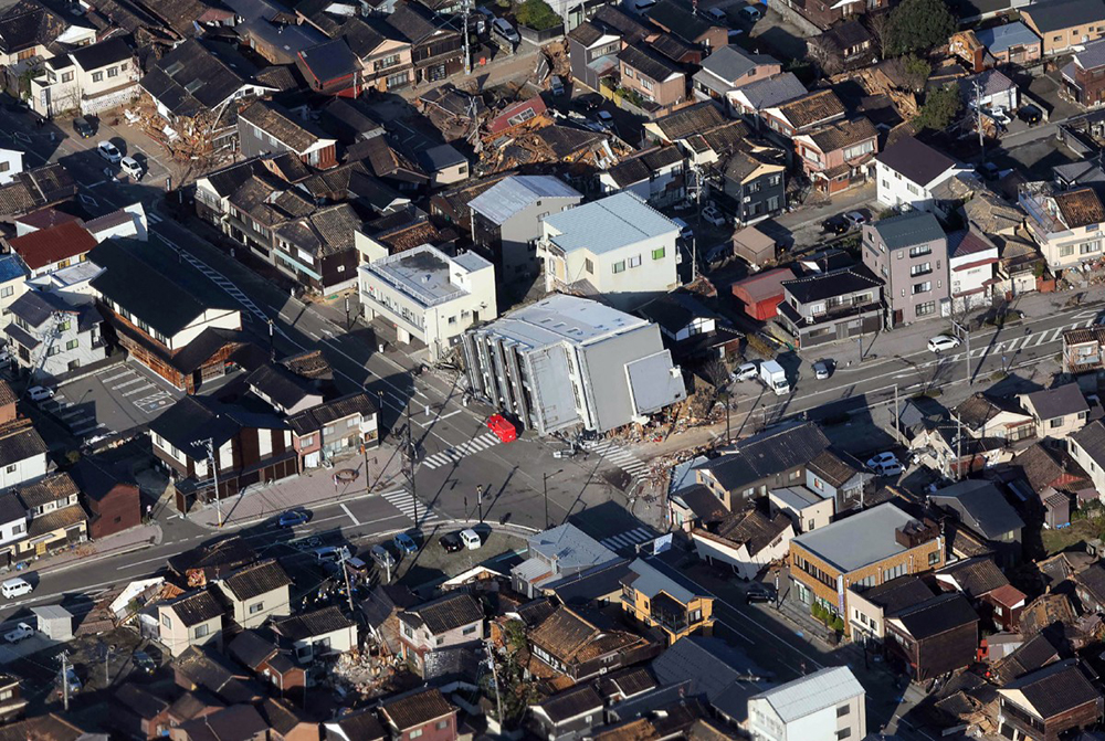 This aerial photo provided by Jiji Press shows a rescue vehicle (C) parked next to a seven-storey building which fell over in Wajima, Ishikawa prefecture on January 2, 2024, a day after a major 7.5 magnitude earthquake struck the Noto region in Ishikawa prefecture. (All Photos by AFP)