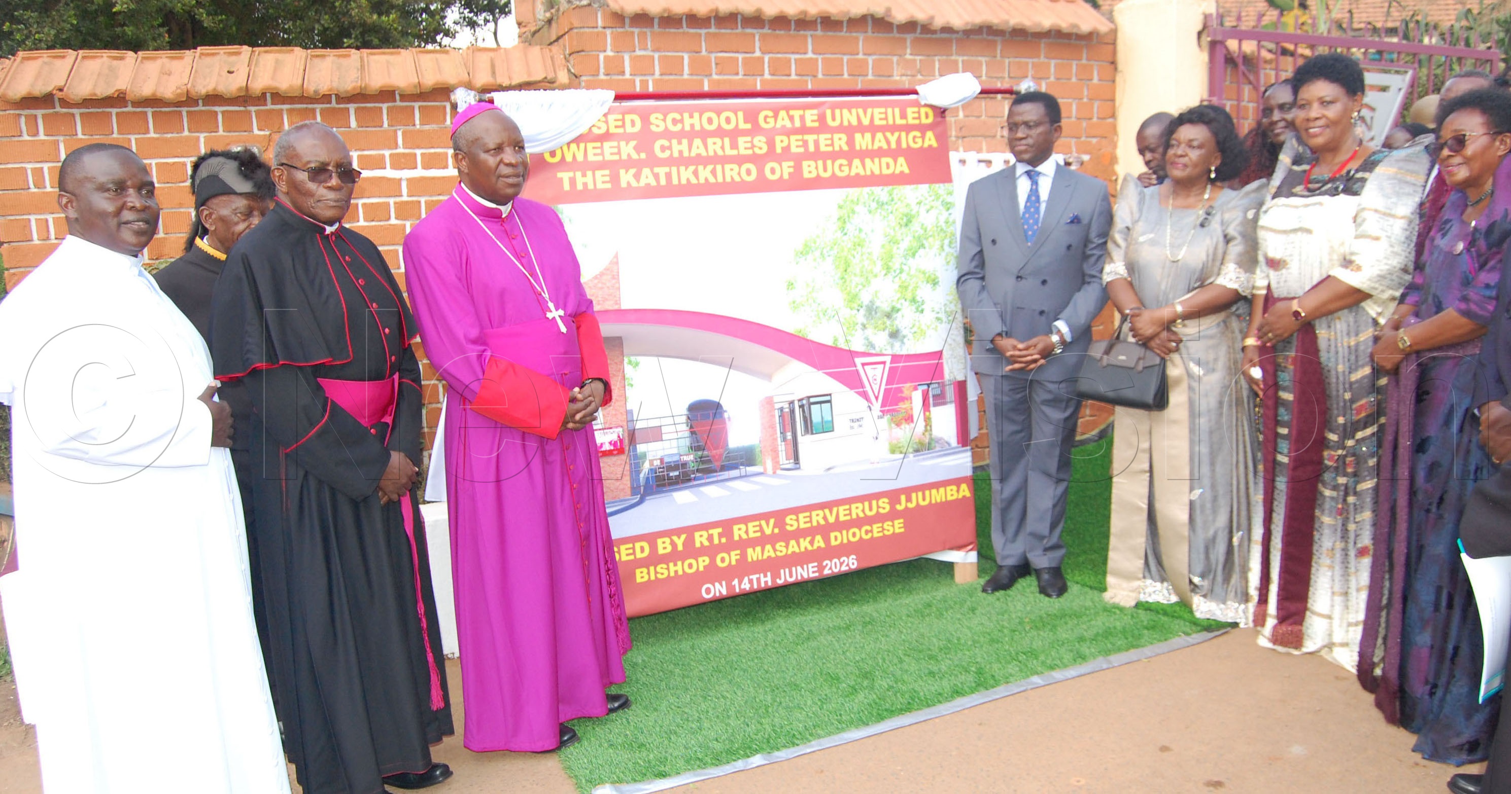 L-R: Fr Dr Joseph Mary Ssebunnya, Msgr. Charles Kasibante, Bishop Serverus Jjumba, Katikkiro Charles Peter Mayiga, Margaret Mayiga, Immaculate Lwanga and Coltilda Nakate Kikomeko standing beside the board of the artistic impression of the proposed school gate of Trinity College Nabbingo after the unveiling/launching of the project on Sunday, June 14, 2026. (Photo by Mathias Mazinga)
