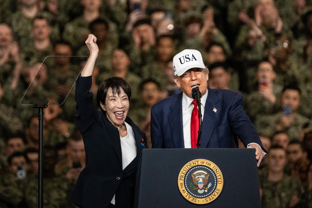 Japan's Prime Minister Sanae Takaichi (L) gestures as US President Donald Trump delivers a speech in front of US Navy personnel on board the US Navy's USS George Washington aircraft carrier at the US naval base in Yokosuka on October 28, 2025.