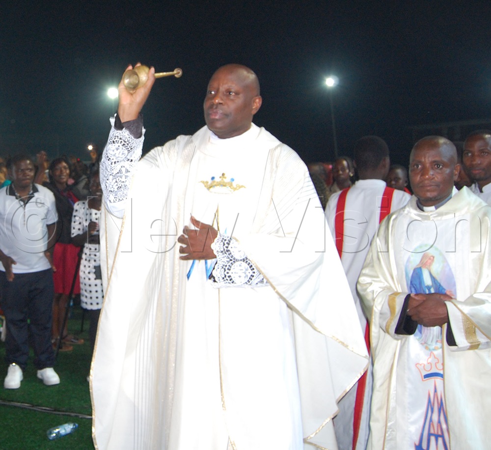 The Vicar-General of Kampala Archdiocese, Msgr. Rogers Kabuye blesses Christians with holy water during the New Year's Eve mass at YES Centre Sports Arena, Nsambya, in Makindye Division on New Year's Eve. (Photo by Mathias Mazinga)