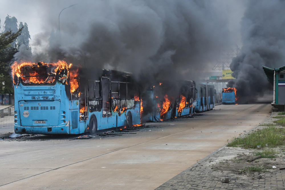 Public buses are set ablaze as clashes erupt in Dar es Salaam on October 29, 2025, during Tanzania’s presidential elections. Tanzania charged more than 100 people on November 7, 2025 with treason over their alleged involvement in protests around October 29 election, according to two judicial sources. (Photo by AFP)