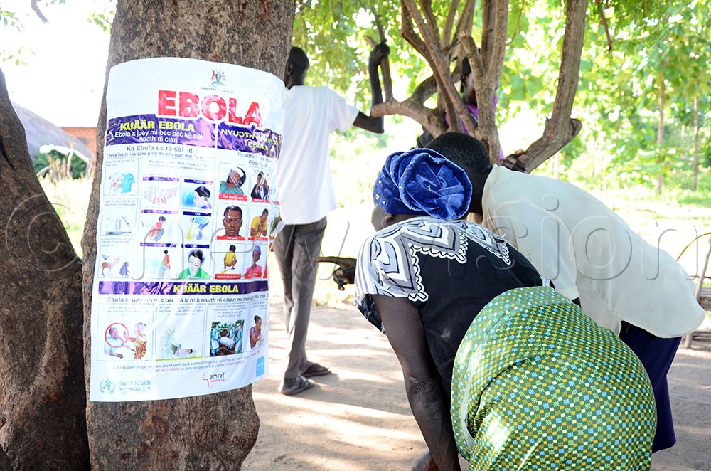 Some of the refugees in Ofua seven Uriama Subcounty in Rhino Camp Refugee Settlement in Terego district reading about Ebola on a ministry of health approved information material. This was during a sensitization community meeting on Ebola that was organized by Amref Health Africa on June 6, 2026. (Credit: Lawrence Mulondo)