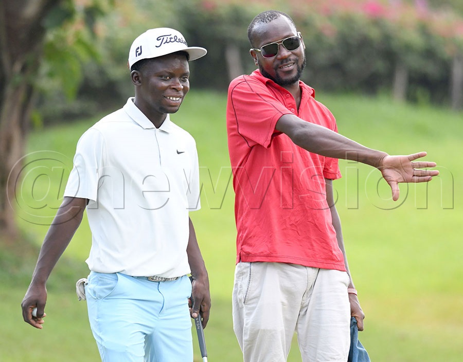 Dominic Musonda (left) interacts with his caddie befoire putting on the 17th green during the opening round. Photo by Michael Nsubuga
