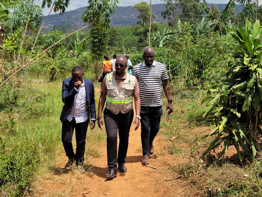 Ivan Akampa, a valuer at the Ministry of Works and Transport, and surveyor Elijah Ssekito are escorted by an Anti-Corruption Unit officer after their arrest. (Photo by Simon Peter Tumwine).