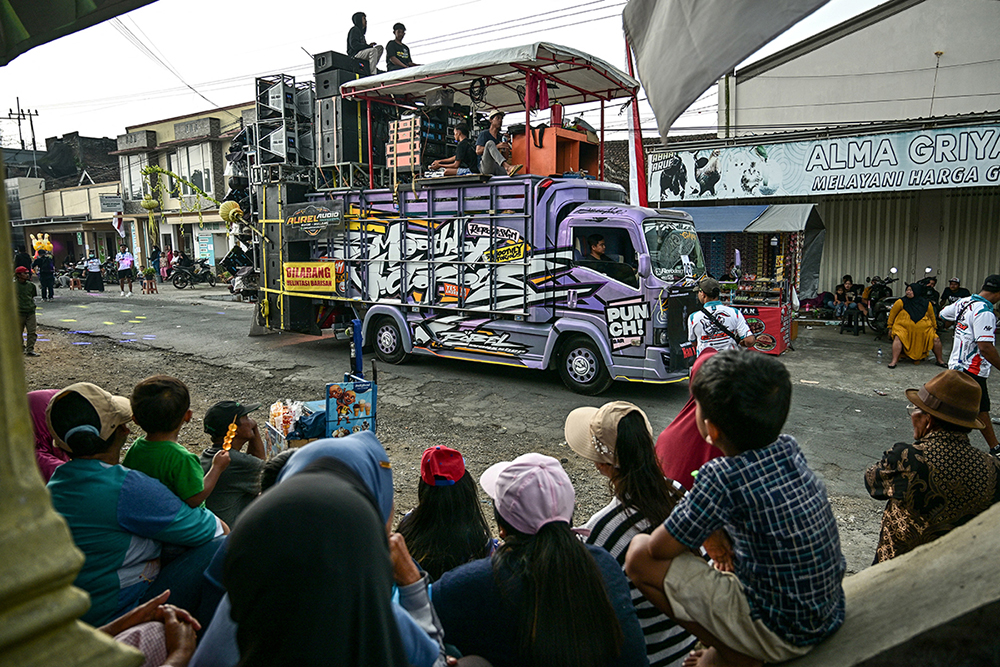 This photo taken on August 9, 2025 shows people watching a truck mounted with a tower of subwoofers and spotlights during a "sound horeg", which loosely means to move or vibrate in Javanese, held as part of Indonesia's 80th Independence Day celebrations in Malang, East Java. (Photo by JUNI KRISWANTO / AFP) 