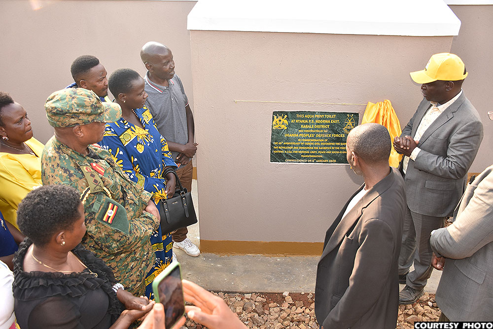 Minister David Bahati unveils a plaque to mark the commissioning of an Aqua Privy toilet constructed by the UPDF at Nyanja Primary School.