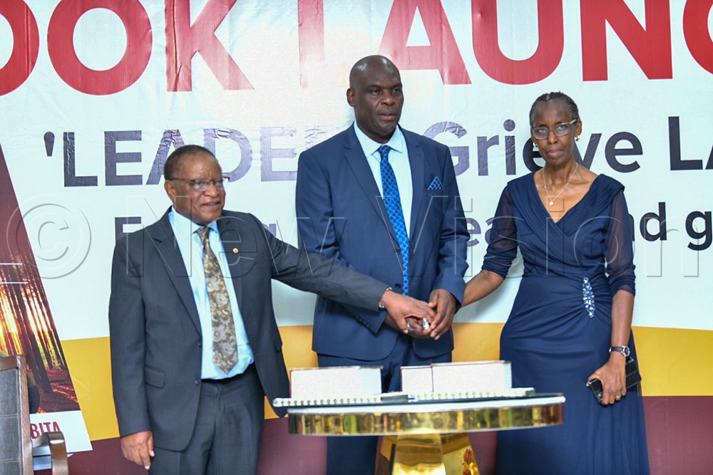 Justice Mike Chibita and wife, Prof. Monica Chibita joined by Prof. Ezra Suruma to cut the cut.