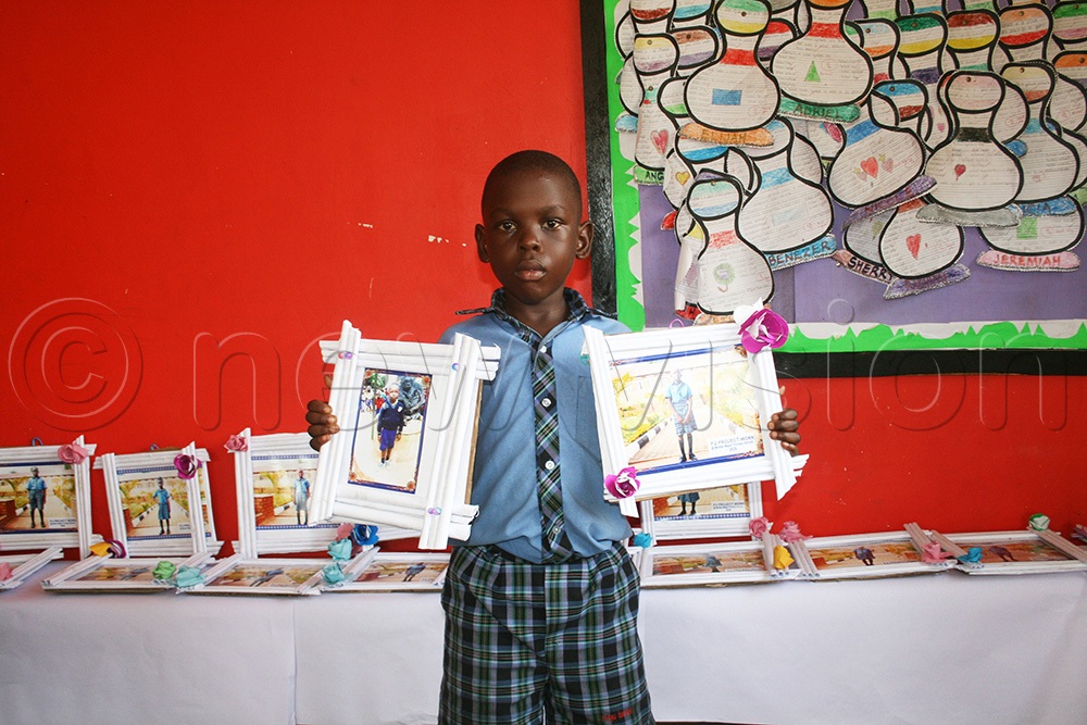 A pupil shows off some of the photo frames he made out of trash. (Photo by Maureen Nakatudde)