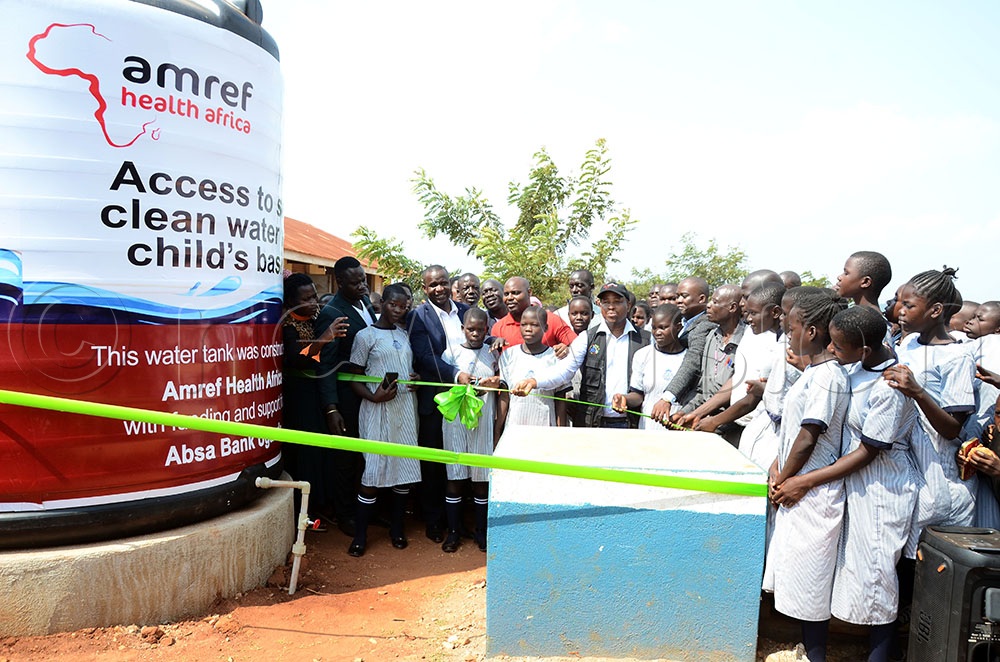 Dr Patrick Kagurusi (C) the Amref Health Africa Uganda Country Manager joins Julius Busingye (in red) the Absa Bank Relationship Manager for Development Organisations, Mayuge district leaders, teachers and learners of Lwanika Modern Primary School to commission a 10,000-litre tank at the school in Bukatube sub county Mayuge district on June 30, 2026. (Credit: Lawrence Mulondo)