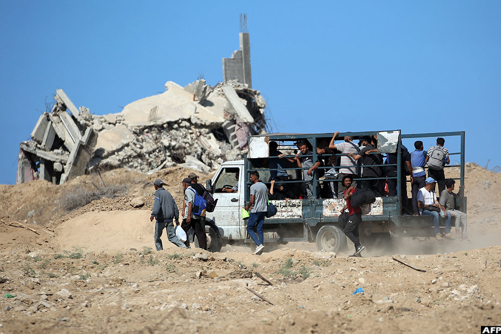 A vehicle transporting passengers to Gaza City moves near the rubble of a destroyed building near Nuseirat in the central Gaza Strip on October 10, 2025
