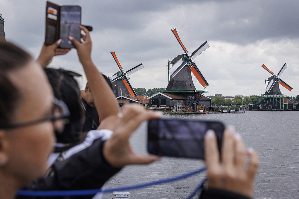 Tourists take a picture in front of windmills in Zaanse Schans, on July 31, 2025. (AFP)