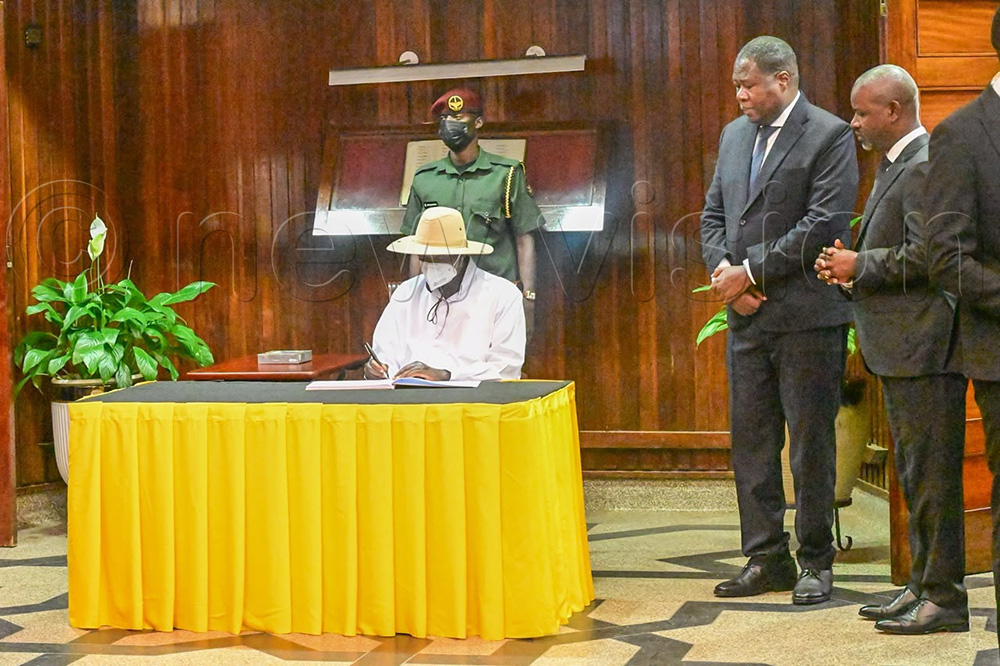 President Museveni signs in Ali's condolence book as Speaker Oboth-Oboth as his deputy look on.