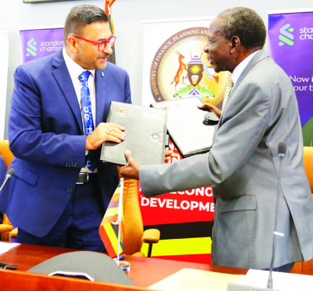 Minisita W&rsquo;ebyensimbi, Matia Kasaija Ne Dayirekita Wa Bbanka Ya Standard Chartered,sujithav Sarangi Nga Bamaze Okuteeka Omukono Ku Ndagaano Ya Ssente Z&rsquo;ebyenkulaakulana.