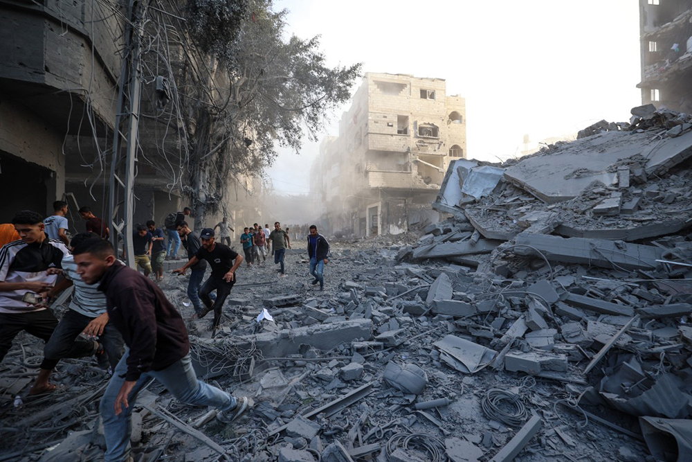 People run for cover following an Israeli strike that targeted a building in the Bureij camp for Palestinian refugees in the central Gaza Strip on October 19, 2025. Gaza's civil defence agency said a series of Israeli air strikes on October 19 killed at least 11 people across the territory, as Israel and Hamas traded blame for violating a ceasefire.