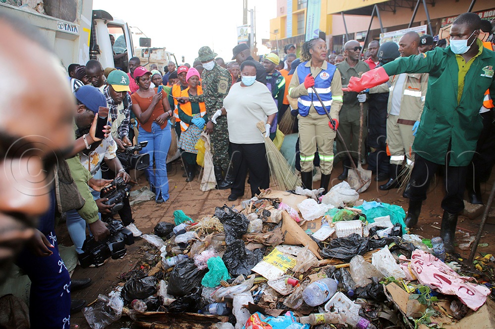 Hoima city Woman MP Nyakato Asinasi with a rake on the right and Prime Minister Robinah Nabbanja with a broom, with residents collecting garbage in Hoima city. (Photo by Peter Abaanabasazi)