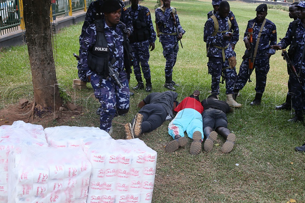 L-R: (on the ground) Idi Waluwu, Robert Biaruhanga, and Wycliffe Tusiime are intercepted by police during a Uganda National Bureau of Standards (UNBS) operation in Kampala while allegedly delivering counterfeit toilet paper. (Photo by Alfred Ochwo)