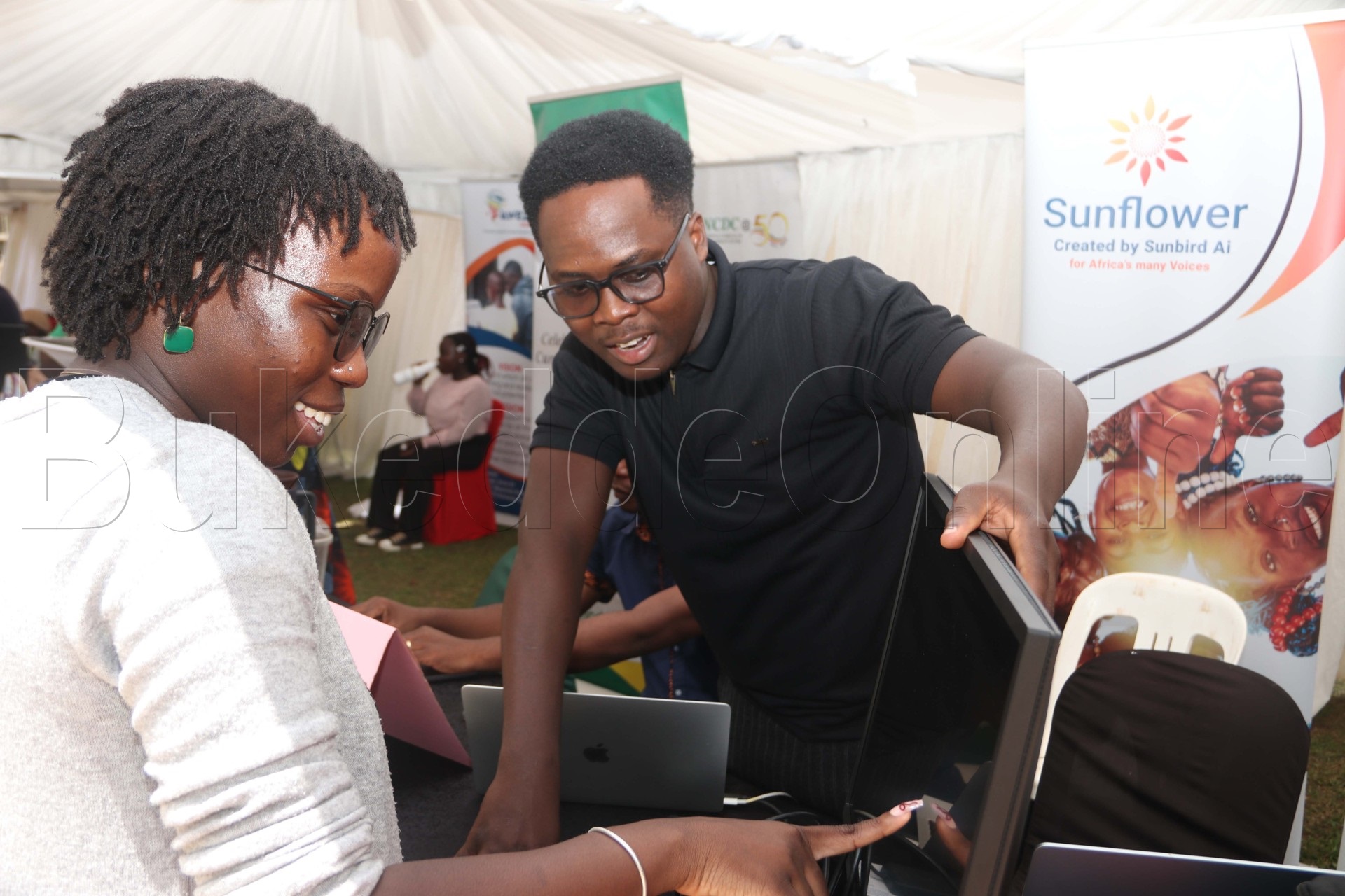 Omuwala n'omuvubuka nga bali ku computer omuli tekinologiya avvuunula ennimi engwiira