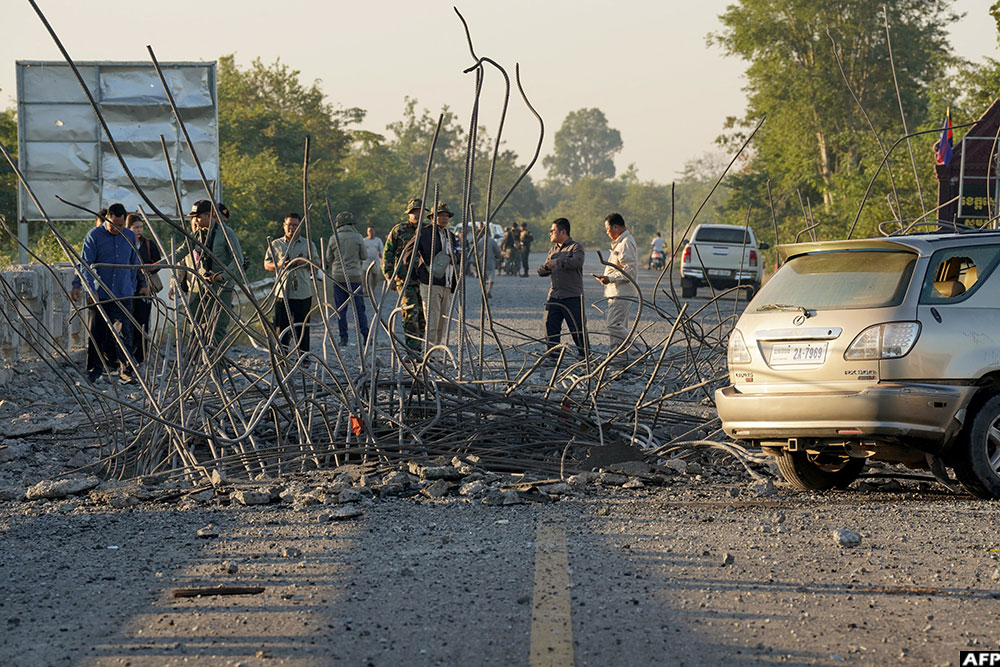 People look at a damaged bridge after Thailand carried out air strikes in an area between Cambodia's Oddar Meanchey and Siem Reap provinces on December 20, 2025