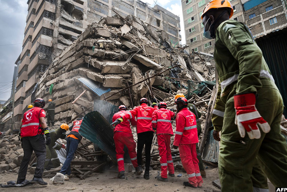 First responders work to clear debris from the collapsed building from the road. (AFP)