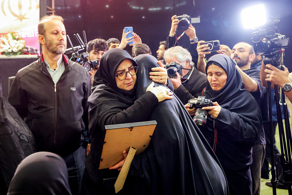 Iran's government spokesperson Fatemeh Mohajerani (C-L) embraces the relative of a victim during a memorial ceremony marking the 40th day of mourning for victims of "terrorism" killed in previous anti-government protests in Iran, at the Tehran Musalla on February 17, 2026. (AFP)