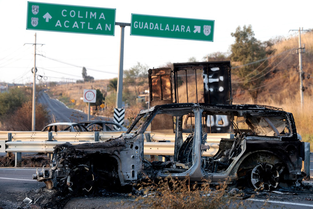 A burned car, allegedly set on fire by organised crime groups in response to an operation to arrest a high-priority security target, is seen on a highway near Acatlan de Juarez, Jalisco state, Mexico on February 22, 2026. (Credit: AFP)