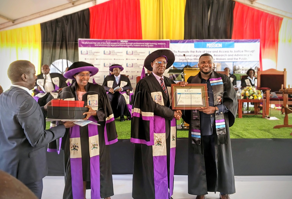 Judiciary PS Dr Pius Bigirimana giving an award to Abdul Katongole as Dr Pamela Tibihikkira-Kalyegira looks on. (Photo by Farooq Kasule)