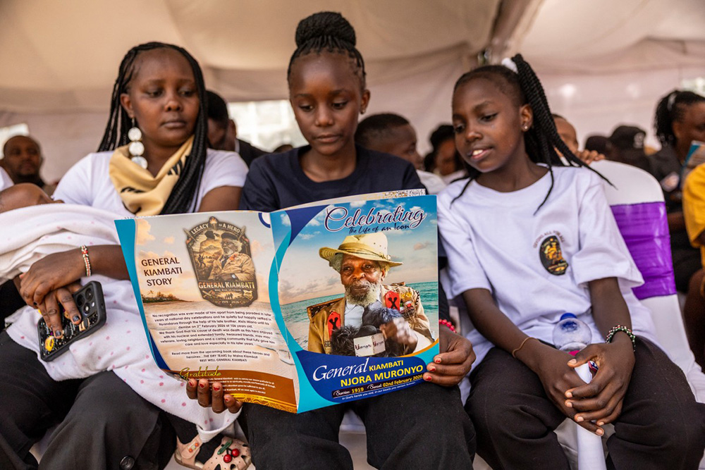  Friends and relatives look at the funeral programme during the burial of one Kenya's last Mau Mau resistance fighter, Christopher Njora Muronyo, known as "General Kiambati", in Nyandarua County on February 14, 2026. (Photo by SIMON MAINA / AFP)
