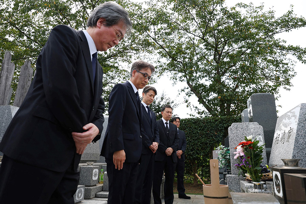 Tetsuro Kamata from Japan's National Police Agency (3rd L) and two other officials from the prosecutor's office apologise in front of the grave of Shizuo Aishima, who was falsely accused of unauthorised export of sensitive equipment and died after prolonged detention, in Yokohama on August 25, 2025. (Photo by JAPAN POOL / JIJI PRESS / AFP) 