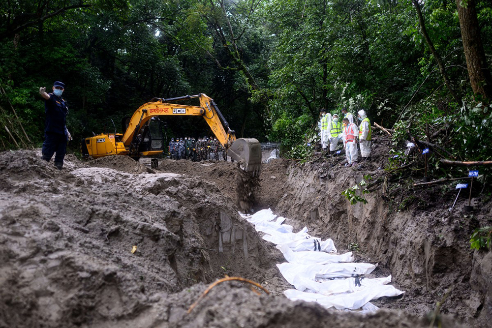 Security personnel conduct the mass burial of unidentified flood victims at the Gokarna forest reserve in Kathmandu on September 1, 2026.