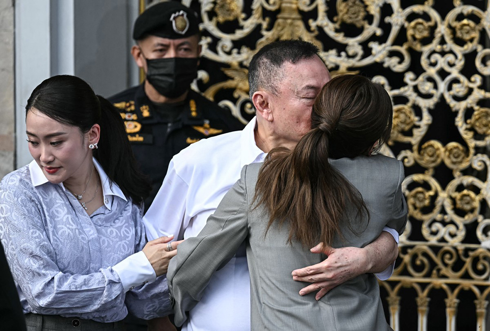 Thailand's former prime minister Thaksin Shinawatra (C) hugs his daughters Paetongtarn Shinawatra (L) and Pintongta Shinawatra Kunakornwong (R) upon his release at Klong Prem Central Prison in Bangkok on May 11, 2026. (AFP)