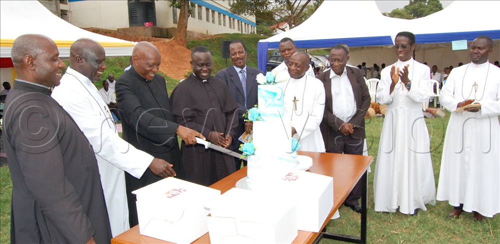 L- R: Bro Aizire (2nd-left), Bro Tamale (4th-left) and other stakeholders cheer as Fr. Dr. Pius Male cuts cake in celebration of the 59th anniversary of Uganda Martyrs High School Lubaga during the function at the school recently.
