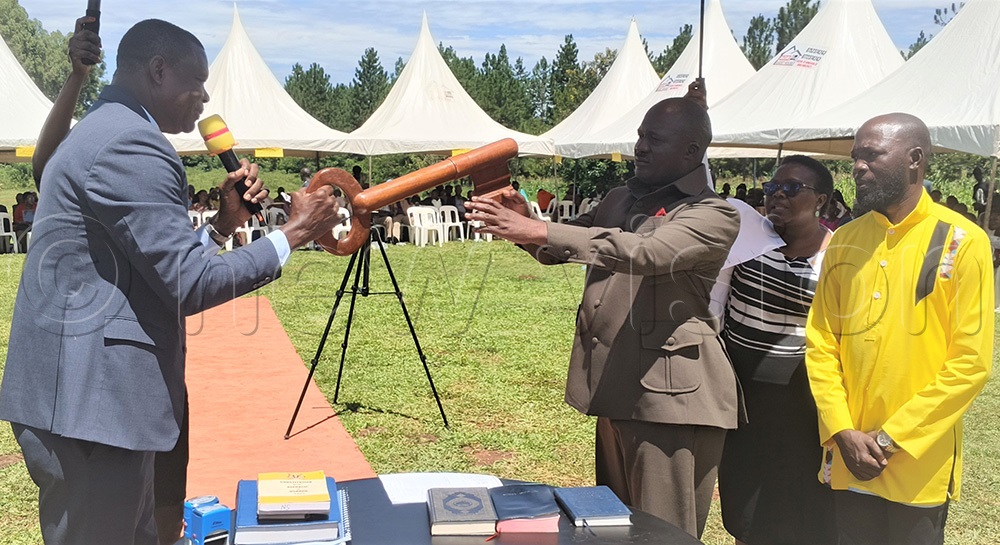 Kamuli LC5 chairperson Kaloli Dhizaala receiving the district's instrument of power. (Photo by Tom Gwebayanga)