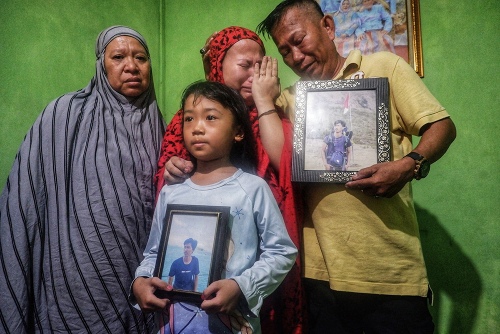 Family members hold portraits of the late Rusdamdiansyah, an online motorcycle taxi driver who was reportedly killed by protesters after being mistaken for a police intelligence officer during a demonstration, at their home in Makassar, South Sulawesi, on September 1, 2025. Indonesian authorities ramped up security on September 1 after six people were killed in unrest over economic hardship that escalated into violent anger against the nation's police force.
