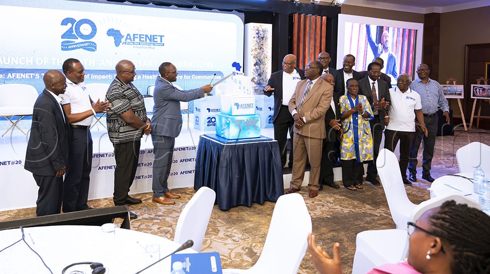 The director of public health at the health ministry Dr Daniel Kyabayinze cutting cake during the AFENET @20celebrations as other officials look on. (Credit: Agnes Kyotalengerire)