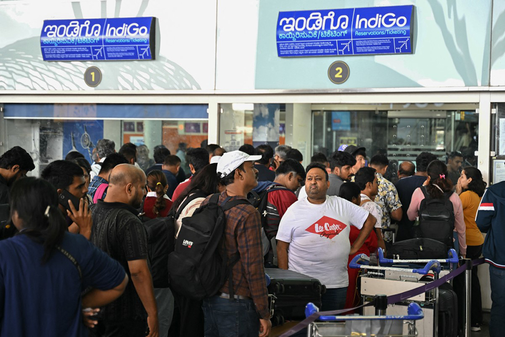 Passengers line up at an Indigo Airlines kiosk at the Kempegowda International Airport in Bengaluru on December 4, 2025. 