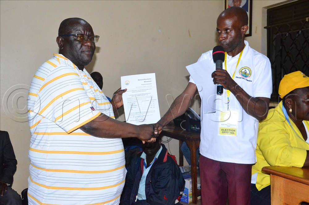 In a white T-shirt is Peter Sserwadda, the Buikwe district NRM Elections officer handing over a declaration form to Mutebi David Ronnie, the Buikwe South winner.