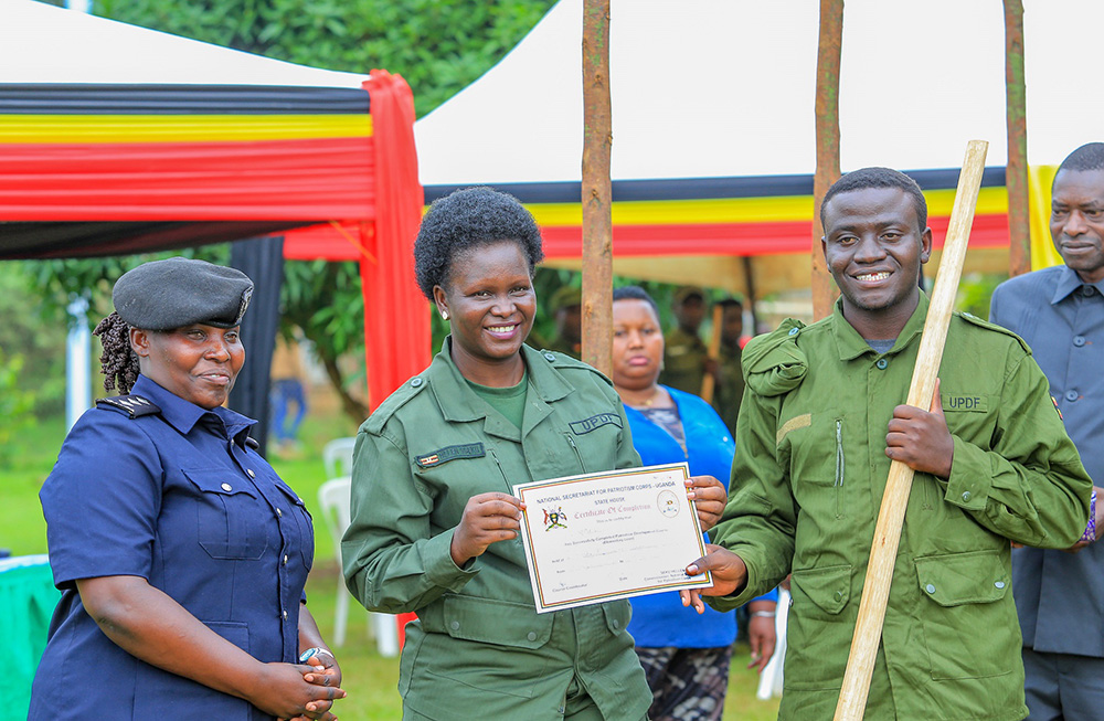The Commissioner of the National Secretariat for Patriotism Corps (NSPC) at State House, Hellen Seku, poses with on of the learners who completed the national patriotism programme after handing him a certificate. (Courtesy photo)