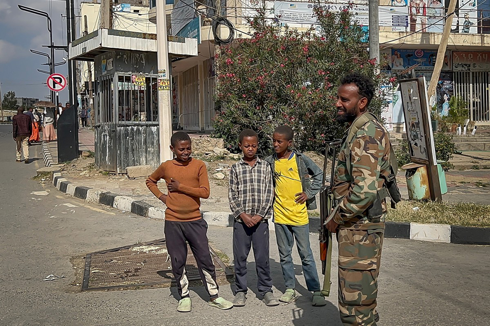 Young residents watch a member of the Ethiopian pro-government Tigray Peace Force (TPF) patrol the streets as Ethiopian federal and allied forces enter the Tigray capital of Mekelle, on October 4, 2026.