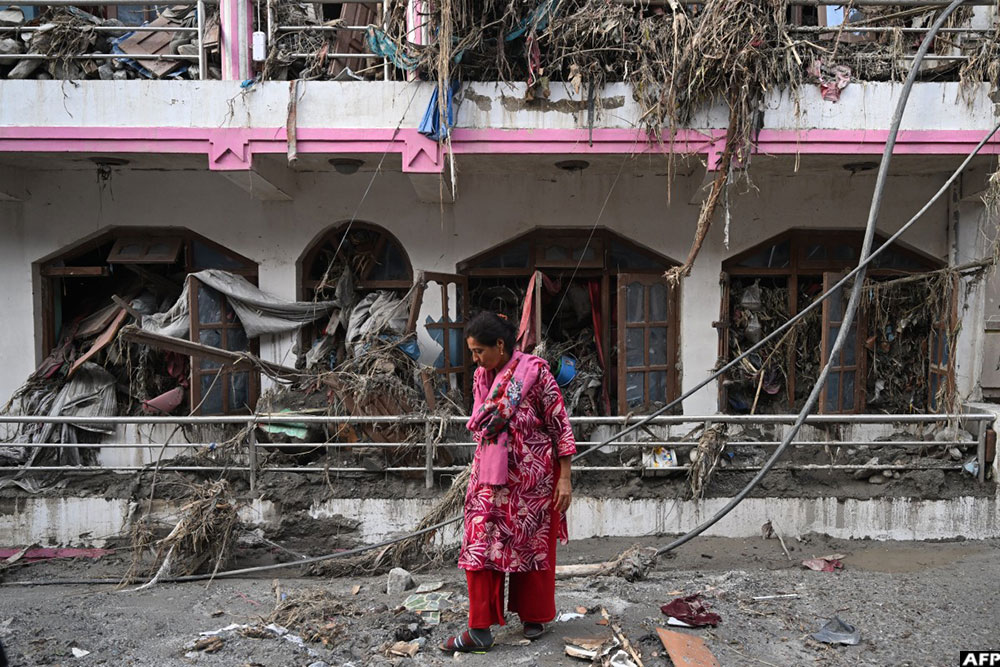 A woman salvages usable materials from her house deluged in sludge following flash floods at Devighat in Nepal’s Nuwakot district on August 28, 2026.