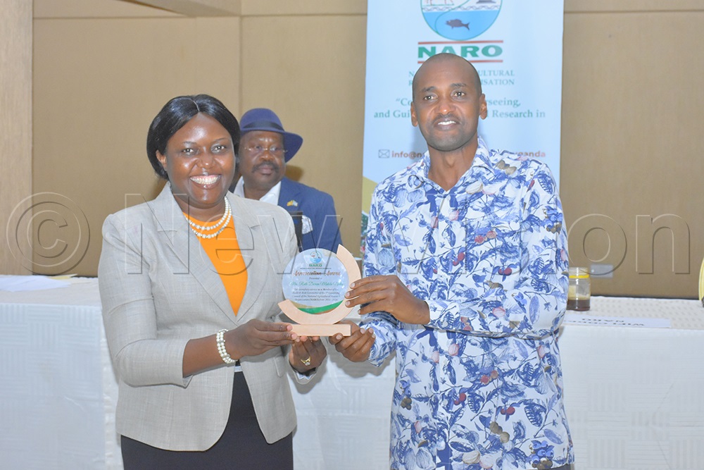 Agriculture minister Frank Tumwebaze awarding Ruth Doreen Mutebe for her exemplary service as a member of the audit and risk committee on the previous council of NARO. (Credit: Julius Luwemba)