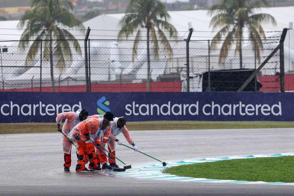Track marshalls sweep water off the track as rain delayed the start of the Formula One Bahrain Grand Prix in Sepang on October 4, 2026.