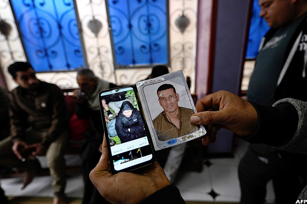 A relative holds up a portrait of Adel Hamed (37) and a picture of him on a phone on a social media network believed to be before he reportedly went missing in the Mediterranean Sea.