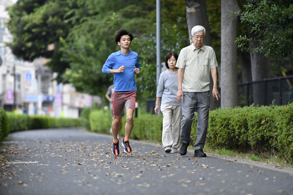 A young man runs past an elderly couple taking a health walk early in the morning on October 1, 2024, in Tokyo, Japan.