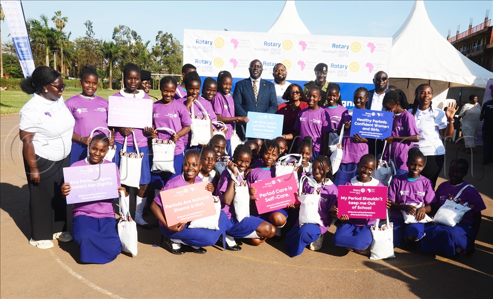 Learners of Nakivubo Blue Primary School in a group picture with Rotary Club of Kasangati members, the commissioner for Gender and Women Affairs in the Ministry of Gender, Labour and Social Development Angela Nakafeero and Director of Parograms Magenta Girls Initiative Gorett Komurembe during the launch of Dignity Kit on Friday